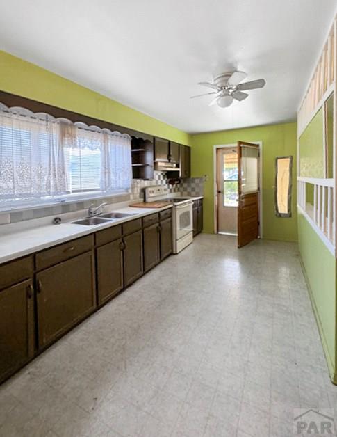 kitchen featuring white range with electric stovetop, light floors, light countertops, a sink, and dark brown cabinets