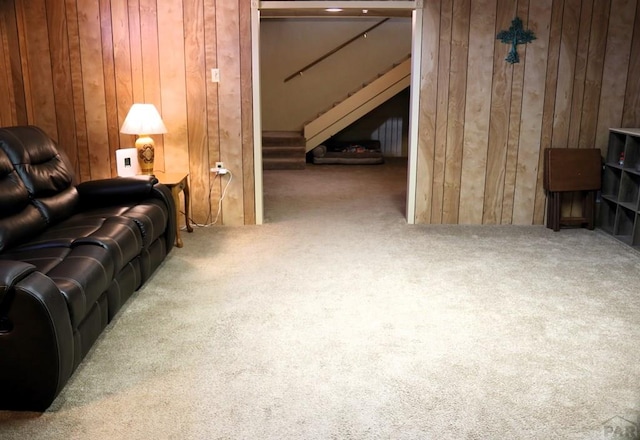 living area with carpet, wood walls, and stairs