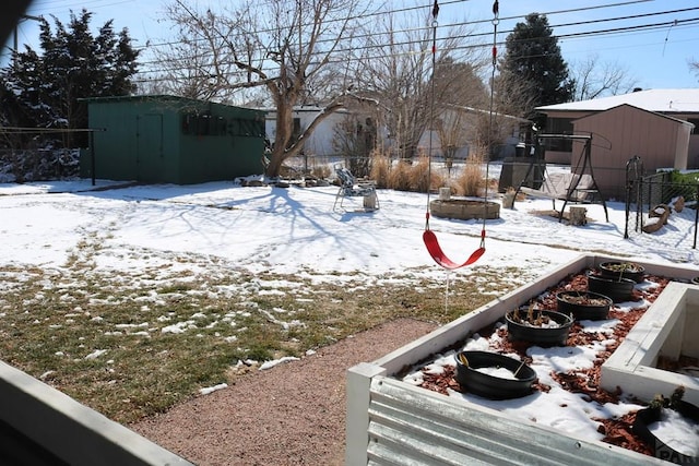 yard covered in snow with fence, an outdoor structure, and a shed