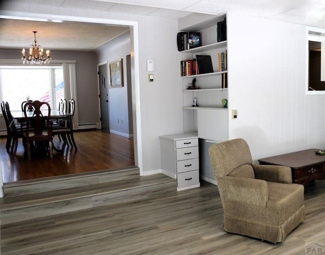 sitting room with dark wood-type flooring, a baseboard radiator, a chandelier, and baseboards