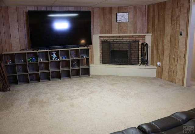 living room featuring carpet flooring, wood walls, and a fireplace