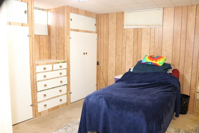 bedroom featuring light carpet and wood walls