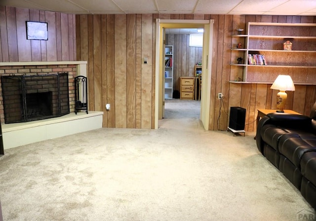 living room featuring a paneled ceiling, wooden walls, carpet, and a fireplace