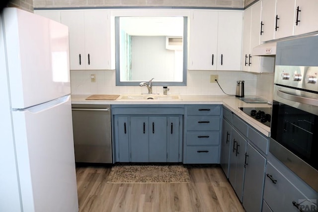 kitchen with under cabinet range hood, appliances with stainless steel finishes, wood finished floors, and white cabinets