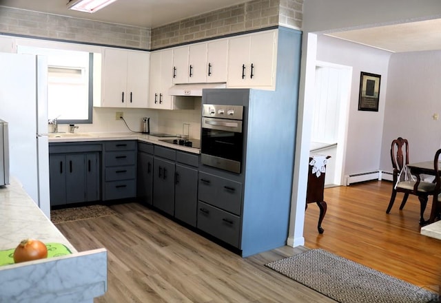 kitchen with freestanding refrigerator, black electric stovetop, light countertops, white cabinetry, and stainless steel oven