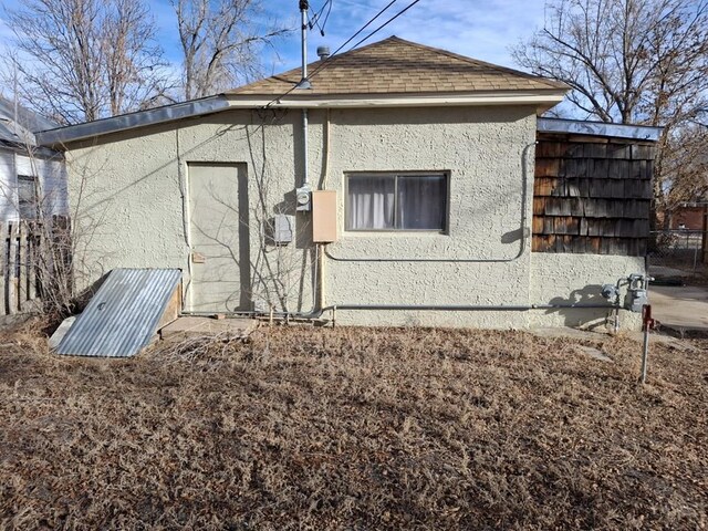 exterior space featuring roof with shingles and stucco siding