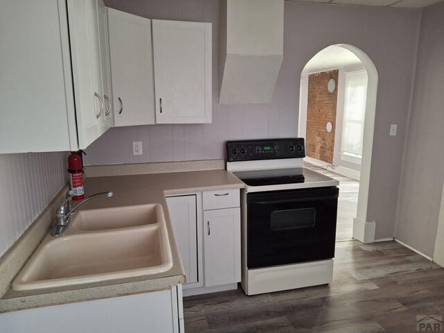 kitchen featuring white cabinets, electric range oven, and light countertops