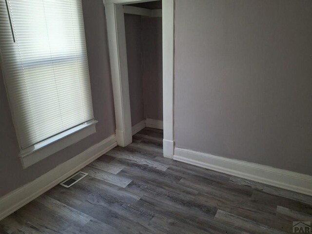 spare room featuring baseboards, visible vents, and dark wood-style flooring