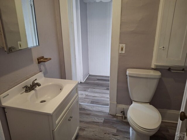 bathroom with baseboards, vanity, toilet, and wood finished floors