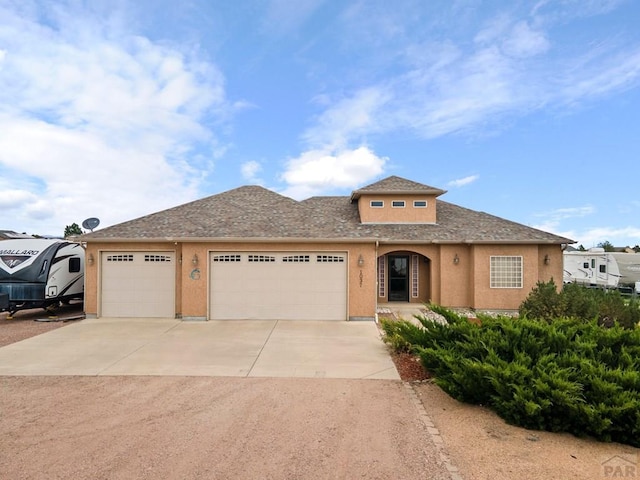 1037 W Desert Sage Dr, Pueblo West, CO 81007 - view of front facade with concrete driveway, a garage, stucco siding, and a shingled roof