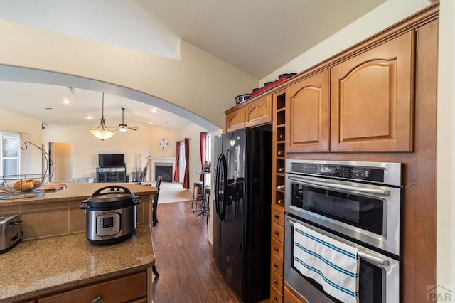 1037 W Desert Sage Dr, Pueblo West, CO 81007 - kitchen with black fridge, stainless steel double oven, lofted ceiling, open floor plan, and dark wood-style flooring