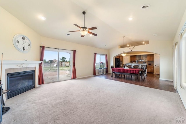 1037 W Desert Sage Dr, Pueblo West, CO 81007 - living area featuring dark carpet, arched walkways, lofted ceiling, ceiling fan, and a tiled fireplace