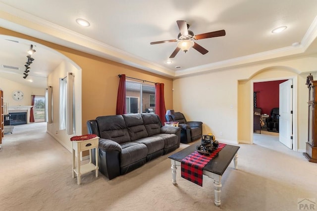 1037 W Desert Sage Dr, Pueblo West, CO 81007 - living room with light colored carpet, ceiling fan, arched walkways, ornamental molding, and a glass covered fireplace