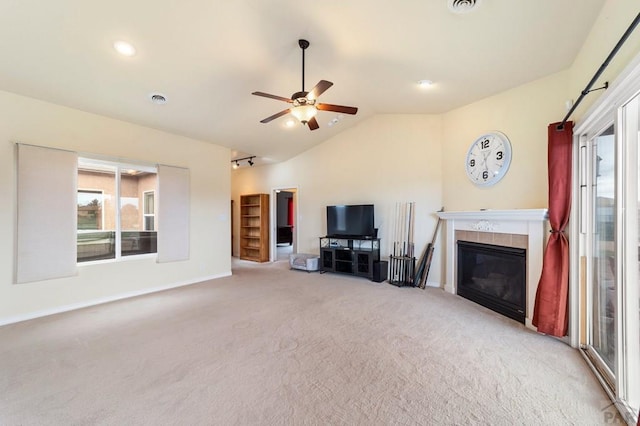 1037 W Desert Sage Dr, Pueblo West, CO 81007 - unfurnished living room with carpet, a tile fireplace, vaulted ceiling, ceiling fan, and baseboards