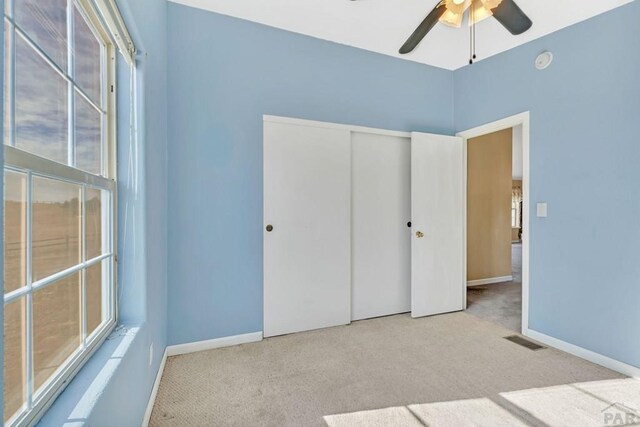 unfurnished bedroom with baseboards, visible vents, a closet, and light colored carpet