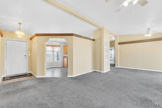 unfurnished living room featuring arched walkways, lofted ceiling, ceiling fan with notable chandelier, baseboards, and dark colored carpet