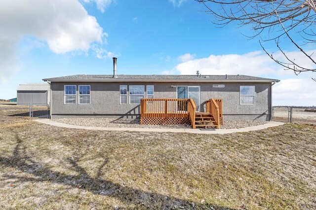 back of property featuring a deck, a yard, fence, and stucco siding