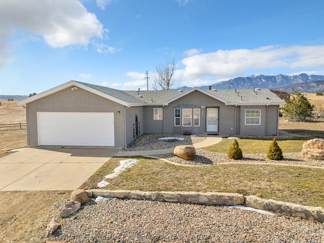 ranch-style house featuring a garage, driveway, stucco siding, a mountain view, and a front yard