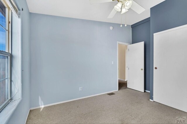 empty room with light carpet, baseboards, visible vents, and a ceiling fan