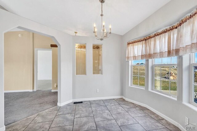 unfurnished dining area featuring carpet floors, arched walkways, lofted ceiling, an inviting chandelier, and tile patterned flooring