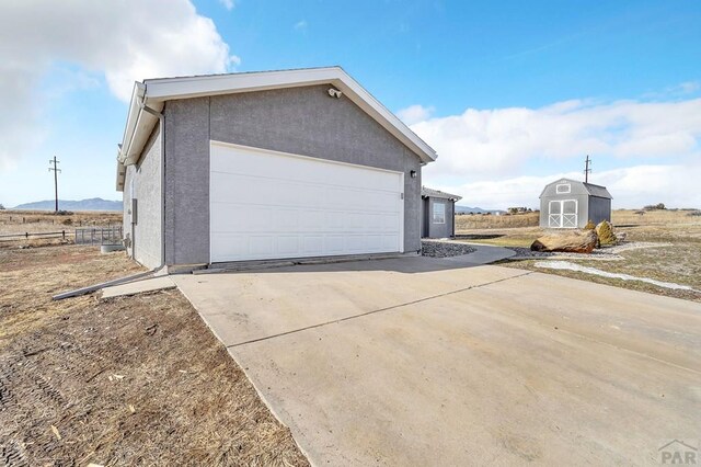 garage with a storage shed and concrete driveway