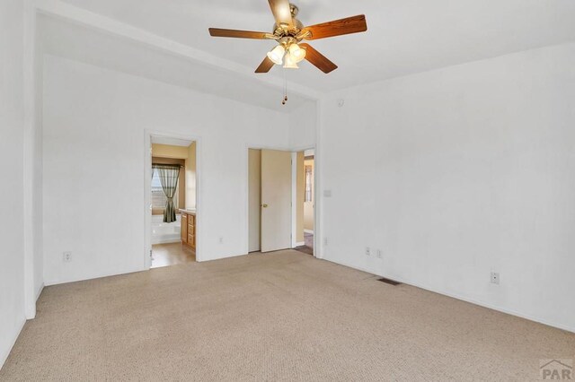 unfurnished bedroom featuring a ceiling fan, light colored carpet, visible vents, and ensuite bath