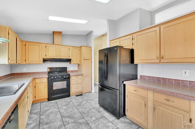 kitchen with black appliances, light brown cabinets, under cabinet range hood, and light countertops