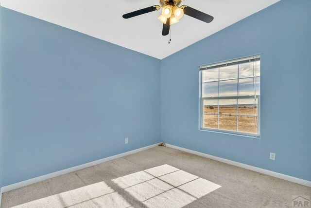 unfurnished room with vaulted ceiling, carpet floors, a ceiling fan, and baseboards