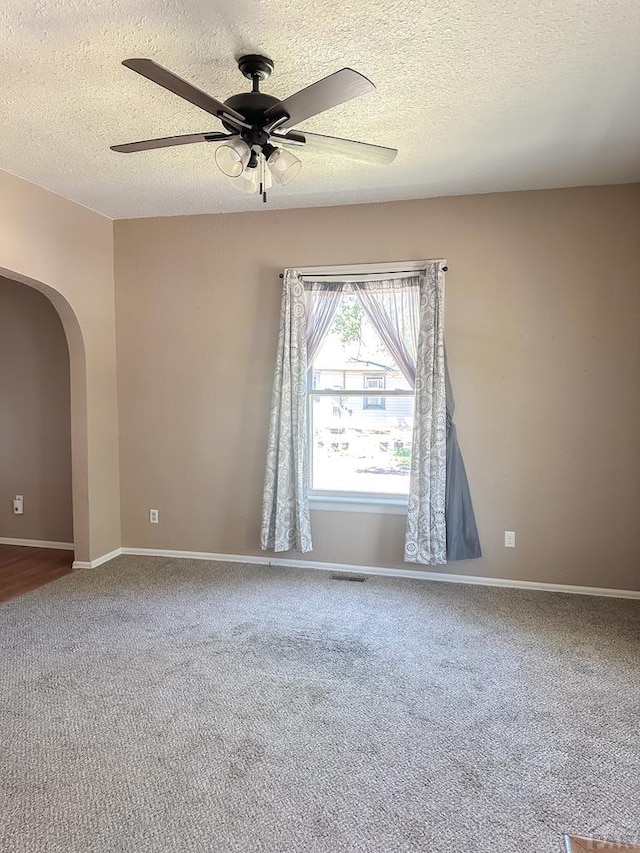 1202 Belleview Ave, La Junta, CO 81050 - carpeted spare room featuring a textured ceiling, a ceiling fan, and arched walkways