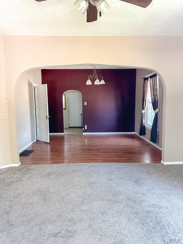 1202 Belleview Ave, La Junta, CO 81050 - carpeted spare room featuring arched walkways, ceiling fan, a textured ceiling, a chandelier, and wood finished floors