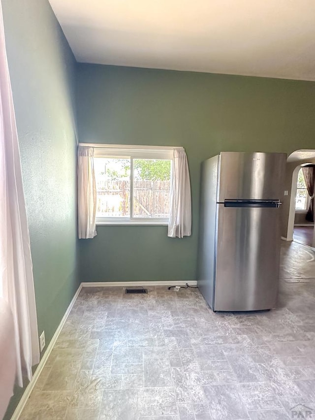 1202 Belleview Ave, La Junta, CO 81050 - kitchen featuring freestanding refrigerator, stone finish flooring, and arched walkways