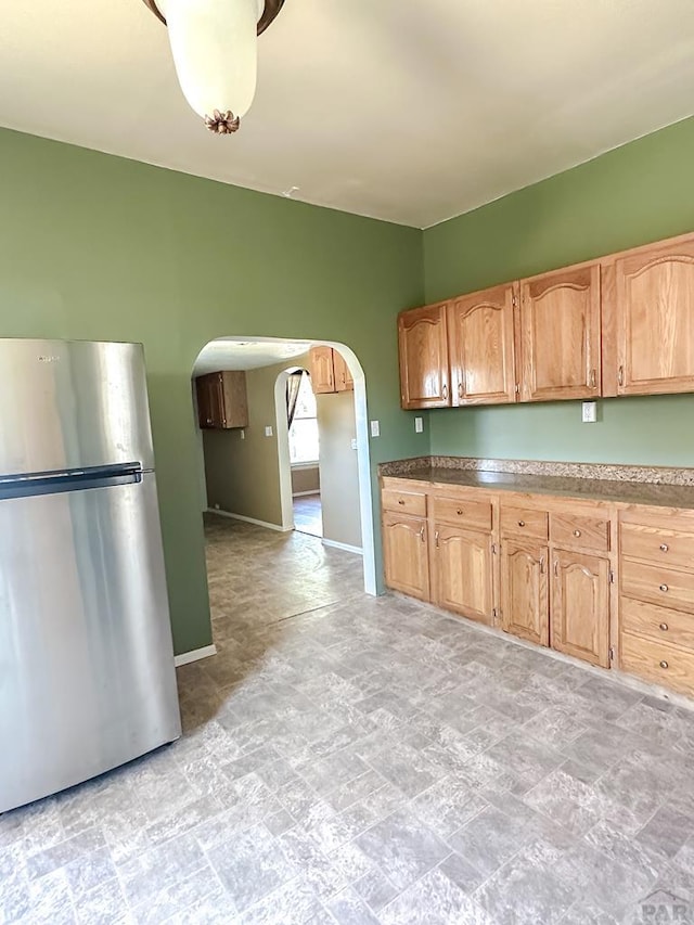 1202 Belleview Ave, La Junta, CO 81050 - kitchen featuring freestanding refrigerator, arched walkways, and stone finish floors