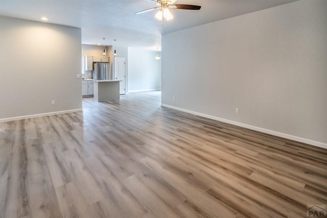 unfurnished living room with light wood-type flooring, baseboards, a ceiling fan, and recessed lighting