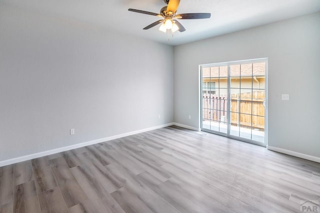 spare room with light wood-type flooring, baseboards, and a ceiling fan