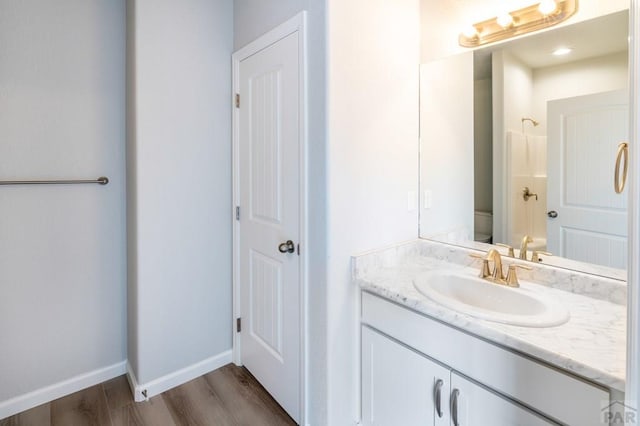 full bath featuring a shower, toilet, vanity, wood finished floors, and baseboards