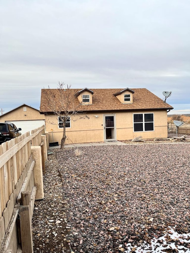 view of side of property featuring a fenced backyard, roof with shingles, and stucco siding