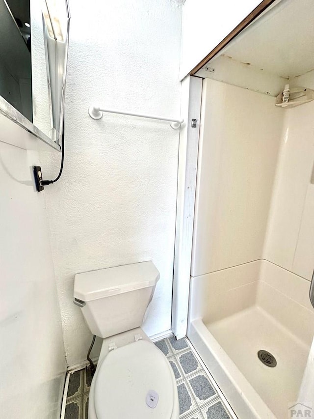 bathroom featuring a shower stall and toilet