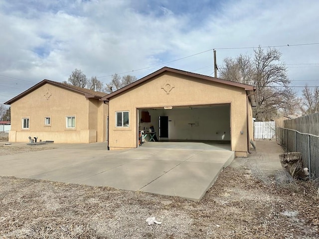 view of front facade featuring fence, driveway, an attached garage, and stucco siding