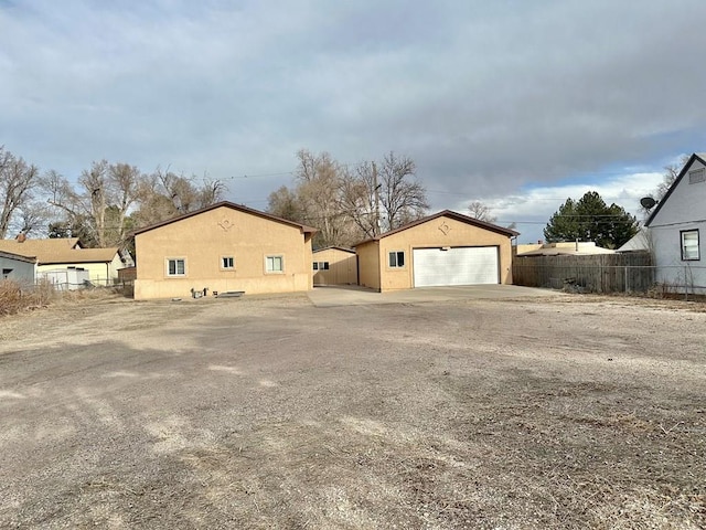 view of property exterior with a detached garage, fence, and an outdoor structure