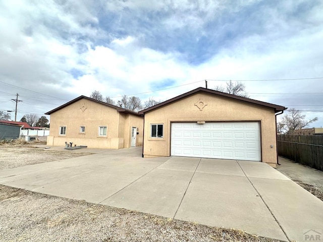 ranch-style house with a garage, fence, and stucco siding