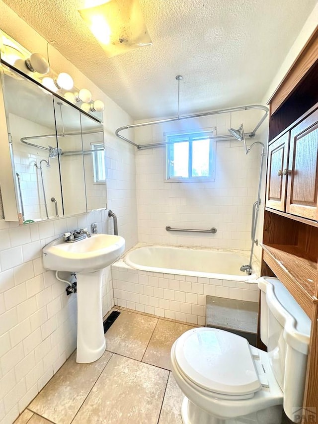 bathroom with a textured ceiling, tiled shower / bath combo, toilet, and tile walls