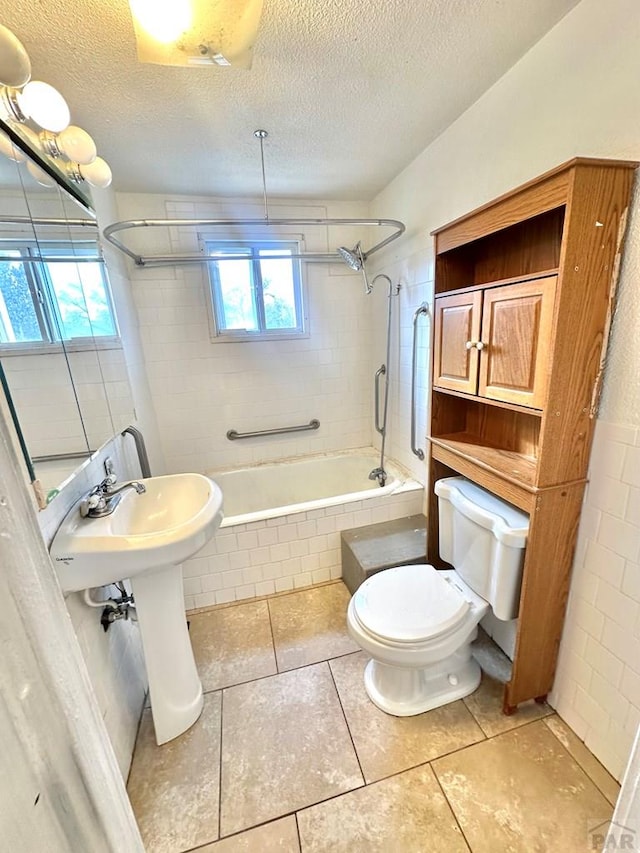 full bath featuring tiled shower / bath combo, a textured ceiling, toilet, and tile patterned floors