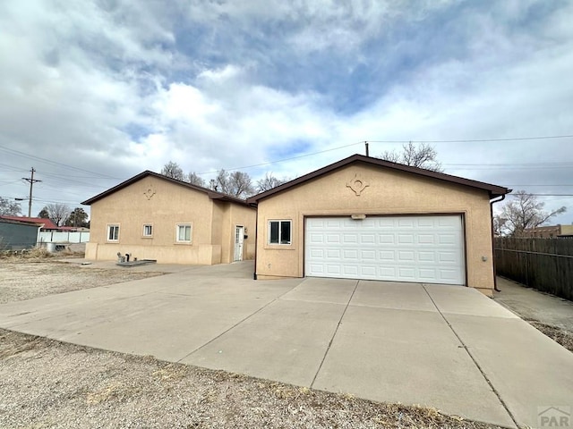 single story home featuring a detached garage, fence, and stucco siding