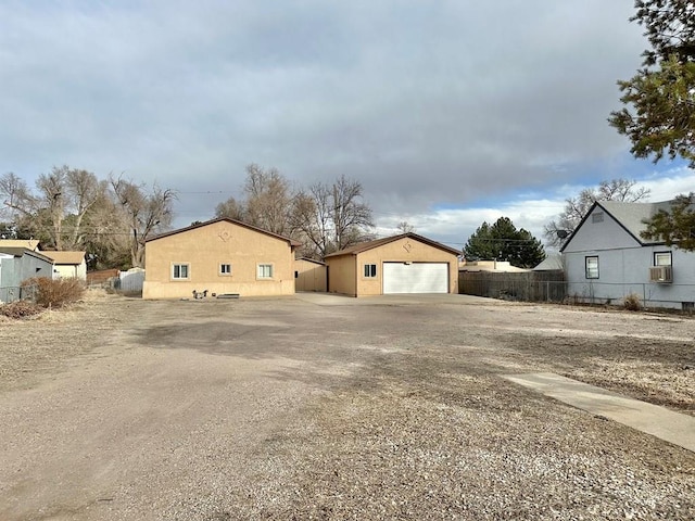 exterior space with an outbuilding, cooling unit, a detached garage, and fence