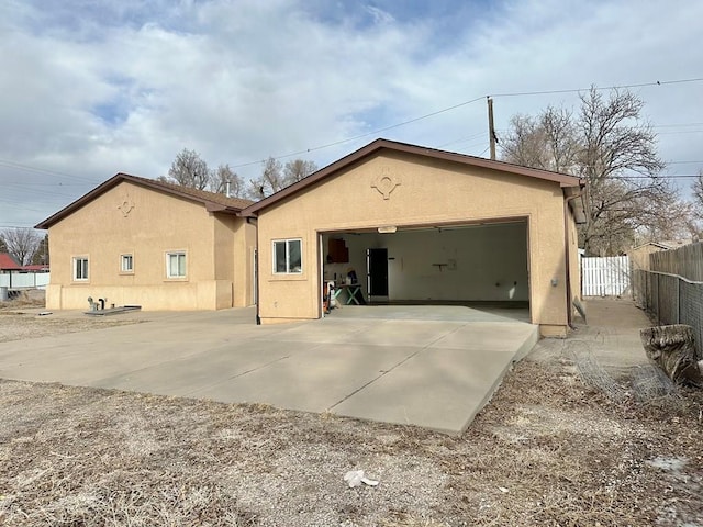 view of front of house featuring an attached garage, driveway, fence, and stucco siding