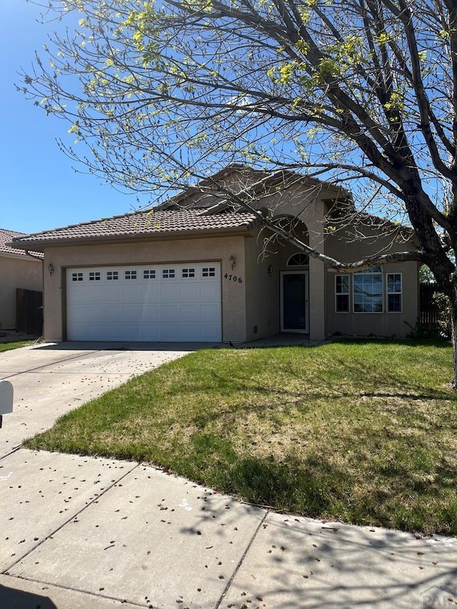 4706 Solar Dr, Pueblo, CO 81005 - view of front facade with a garage, a front yard, stucco siding, a tiled roof, and driveway