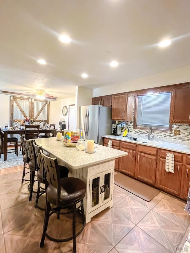 kitchen featuring a kitchen bar, decorative backsplash, a center island, and freestanding refrigerator