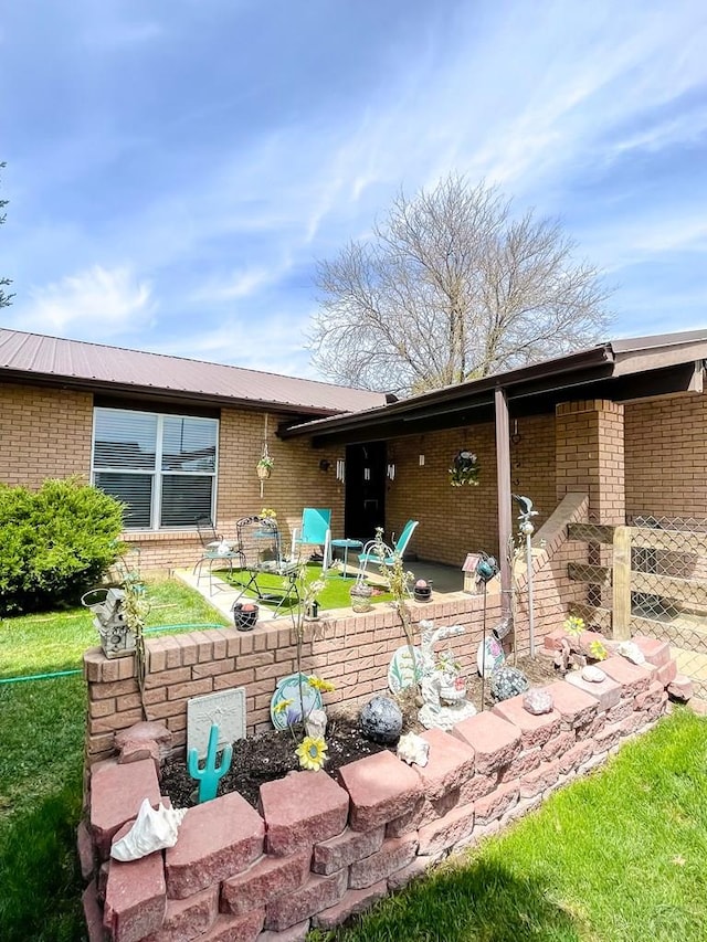 rear view of house with brick siding, a patio area, and metal roof
