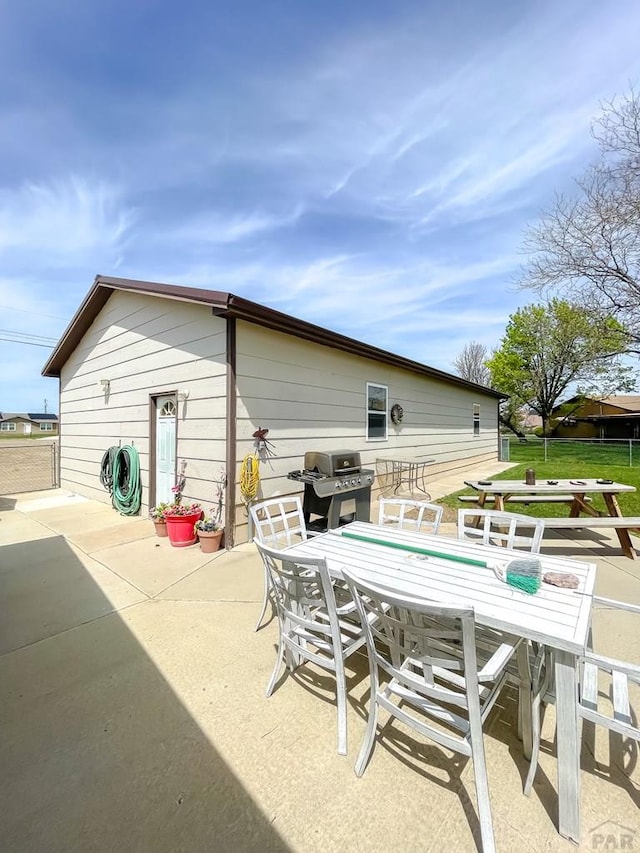 back of house featuring outdoor dining area, a patio area, and a lawn