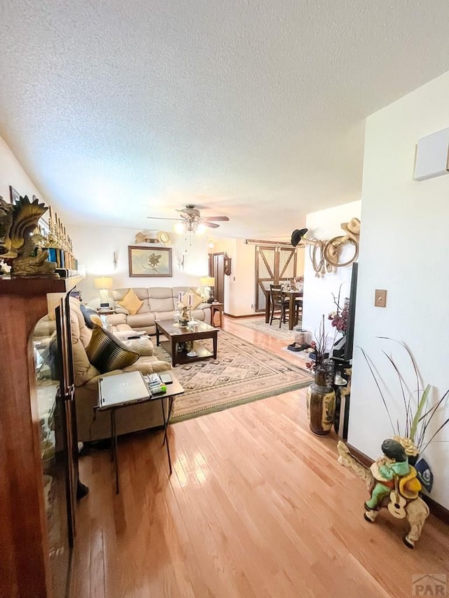 living area with a ceiling fan, wood finished floors, and a textured ceiling